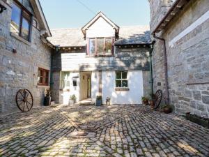an old stone house with a cobblestone driveway at The Mews in Bodmin