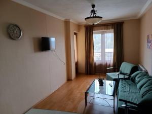 a living room with a green couch and a glass table at Bakuriani-Otin in Bakuriani