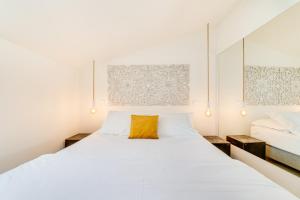 a bedroom with a large white bed with a yellow pillow at Chiado 44 in Lisbon