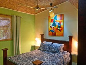 1 dormitorio con 1 cama y una pintura en la pared en Montaña Linda Hostel Orosi, en Orosí