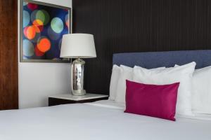 Cama blanca con almohada morada y lámpara en Hotel Lucent en Menlo Park