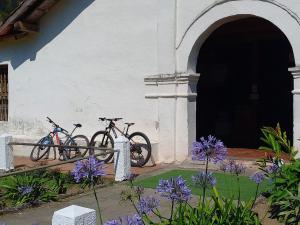 dos bicicletas estacionadas al lado de un edificio con flores púrpuras en Montaña Linda Hostel Orosi en Orosí