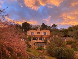 une maison sur une colline avec un coucher de soleil en arrière-plan dans l'établissement L'Olivette - Mas Provencal, Panoramic View & Pool, à Callian