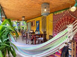 a hammock hanging in a room with a table at Montaña Linda Hostel Orosi in Orosí