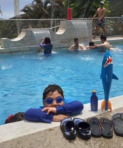a young boy laying in a swimming pool with his arms crossed at Montaña Linda Hostel Orosi in Orosí