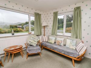 a living room with a couch and a table and windows at Llwynon in Aberystwyth