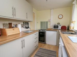a kitchen with white cabinets and a sink and a microwave at Llwynon in Aberystwyth