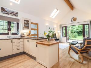 a kitchen with white cabinets and a living room at Bryher Cottage in Helston
