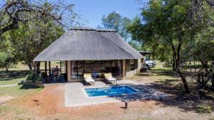 a hut with a pool and a man sitting in front of it at Zebula Golf Estate & Spa Executive Holiday Homes in Mabula