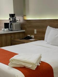 a hotel room with two beds and a microwave at HOTEL LOS ROBLES in Nuevo Laredo