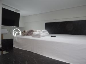a white bed with towels and a television in a room at ZANI APART HOTEL 520i in Porto Velho