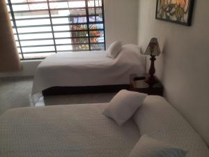 een slaapkamer met 2 bedden, een lamp en een raam bij RAKIRA SUITES APARTAHOTEL CAMPESTRE in Ráquira