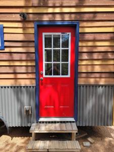 a red door on the side of a wooden house at NEW Lovable Mountain Tiny Home near Cripple Creek in Cripple Creek