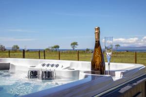 a hot tub with a bottle of champagne and a glass at Litua Luxury self-catering with stunning sea views in Arisaig