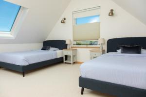Litua Luxury self-catering with stunning sea views في آريسايغ: سريرين في غرفة بها نافذتين