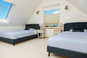 two beds in a room with two windows at Litua Luxury self-catering with stunning sea views in Arisaig