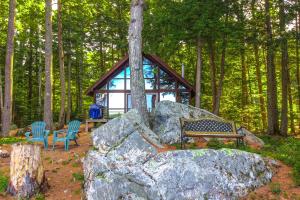 a cabin in the woods with a bench and a large rock at Lake Waukewan Chalet in Meredith +16 photos
