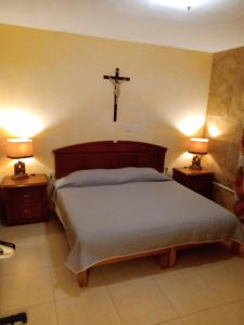 a bedroom with a bed with a cross on the wall at La Casa Rosa Guanajuato in Guanajuato
