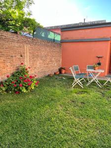 a yard with two chairs and a table and flowers at Casa vero in San Antonio de Areco