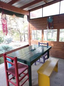a wooden table and chairs in a room with windows at Árbol de Oro - Terrafirme in Villa Yacanto