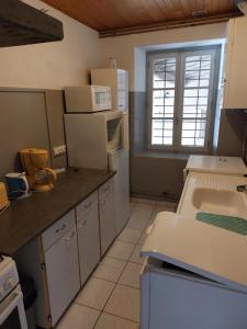 a kitchen with white appliances and a large window at La Ginelle - Appartement Terrasse in Airoux
