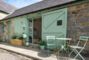 un cobertizo verde con 2 sillas y una puerta en The Offshot, en Alnwick