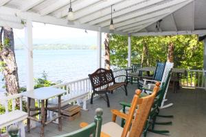 a porch with tables and chairs and a view of the water at Cottage on Geneva Point in Moultonborough