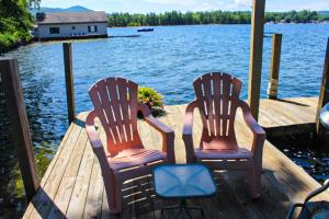 2 chaises assises sur un quai à côté de l'eau dans l'établissement Varney Point Studio, à Gilford