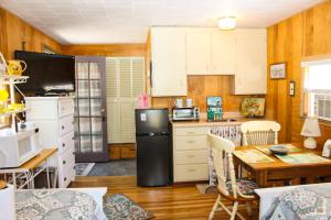 a kitchen with white cabinets and a black refrigerator at Varney Point Studio in Gilford