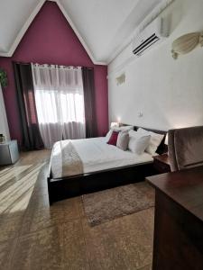 - une chambre avec un grand lit et des murs violets dans l'établissement L'Address Bar-Piscine-Restaurant, à Cotonou