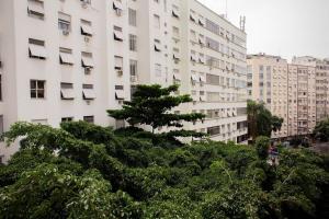 a large white building with a tree in front of it at Quarto e sala em Ipanema perto da praia in Rio de Janeiro