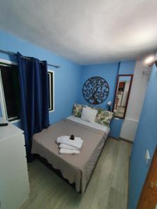 a bedroom with blue walls and a bed with towels on it at Terraza Alcalá in Alcalá