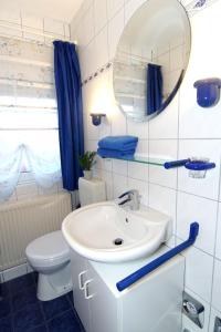 ein Badezimmer mit einem Waschbecken, einem WC und einem Spiegel in der Unterkunft Ferienwohnung Doris in Norddeich