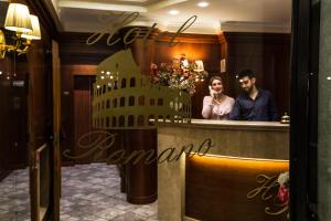 een man en een vrouw die achter een toonbank in een salon staan bij Hotel Romano in Rome