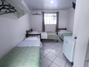 a small room with two beds and a window at HOTEL MORADA DO SOL in Pontal do Paraná