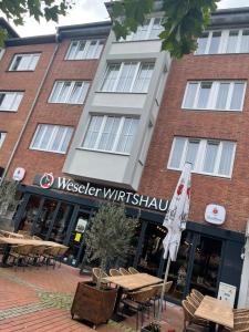 a hotel with tables and chairs in front of a building at Weseler Wirtshaus Appartements in Wesel