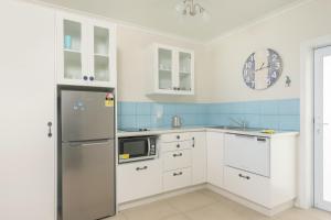 cocina con armarios blancos y nevera en Vaima Beachfront Apartments, en Rarotonga
