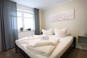 1 dormitorio con 2 camas con sábanas blancas y ventana en Schaake Hooksiel zum Wohlfühlen, en Hooksiel