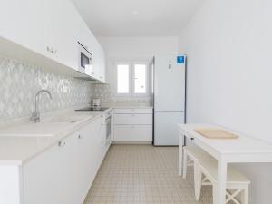 a white kitchen with white cabinets and a refrigerator at Pasitoblanco Porto Mare 44 Seaview Villa private heated pool in Pasito Blanco
