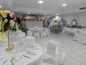 un salón de banquetes con mesas blancas, sillas y flores en Hotel Tower House Suites, en Panamá