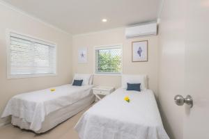two beds in a room with white walls and windows at Vaima Beachfront Apartments in Rarotonga