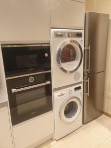 a kitchen with a washer and dryer next to a refrigerator at London Luxury 3 bedroom 2 bathrooms flat 1 min to Redbridge Station FREE parking & WIFI in Wanstead