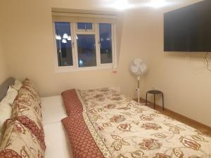 a bedroom with a bed and a window and a fan at London Luxury 3 bedroom 2 bathrooms flat 1 min to Redbridge Station FREE parking & WIFI in Wanstead