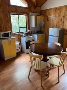 cocina con mesa y sillas en una habitación en Cascadas del Llaima, Cabaña Pájaro Carpintero, en Curacautín