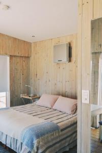 1 dormitorio con 1 cama y TV en la pared en Remanso del Diablo, en Punta del Diablo