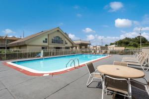 una piscina con mesa y sillas junto a un edificio en Best Western University Inn en Tuscaloosa