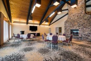 Best Western Plus NorWester Hotel & Conference Centre في ثاندر باي: قاعة اجتماعات مع طاولات وكراسي وجدار حجري