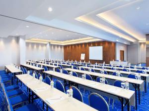 a large lecture hall with tables and blue chairs at Ibis Budget Bandung Asia Afrika in Bandung