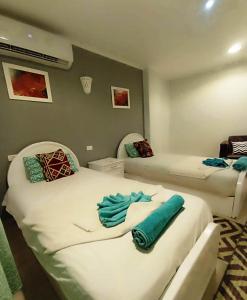 - 2 lits dans une chambre avec des serviettes bleues dans l'établissement Nefertarie Guest House, à Louxor