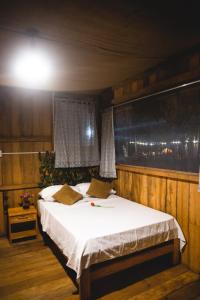 1 dormitorio con 1 cama con sábanas blancas y ventana en PAMPA HERMOSA LAKE RESORT en Puerto Maldonado